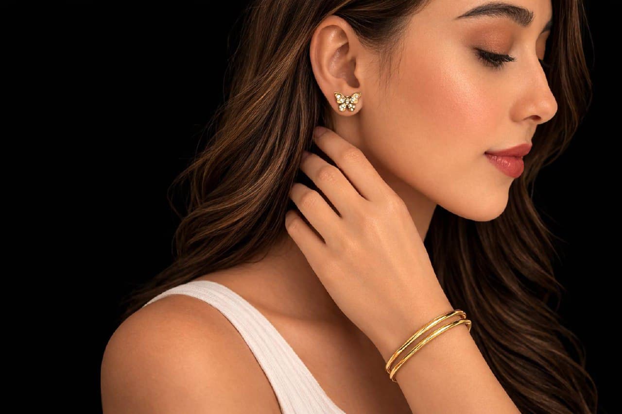 Woman wearing Zevras butterfly CZ studs and gold bangles
